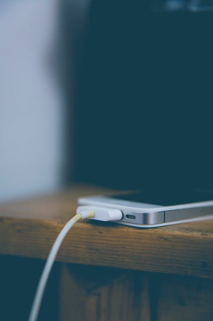 Person plugging a USB-C cable into a phone while charging with a power adapter