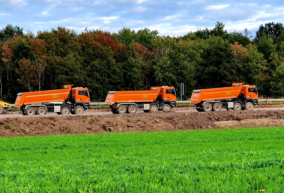 Dump trucks waiting near a loading area while operators spot and load