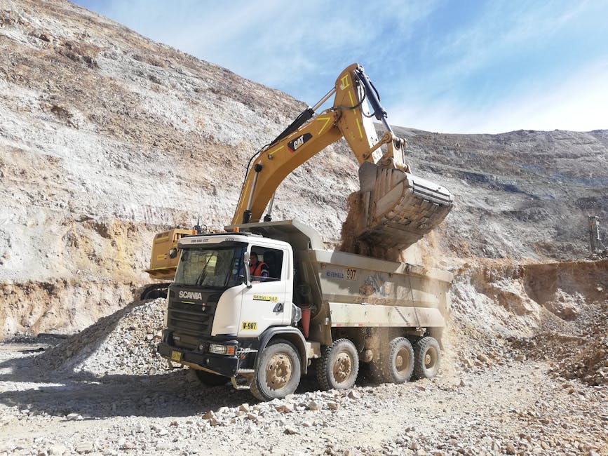 Compact excavator loading a dump truck during earthmoving operations
