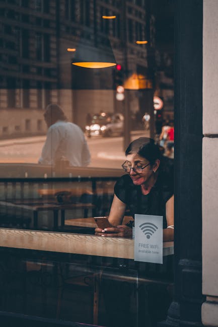 Person holding phone checking Wi‑Fi signal near a router and extender setup