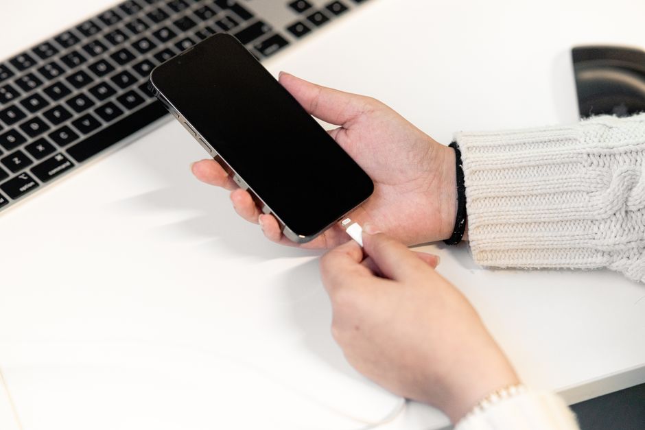 Close-up of a person checking a phone charging status and cable connections