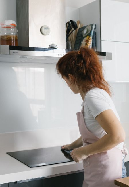 Person cooking at a stove while an air purifier or range hood runs as particles rise and fall